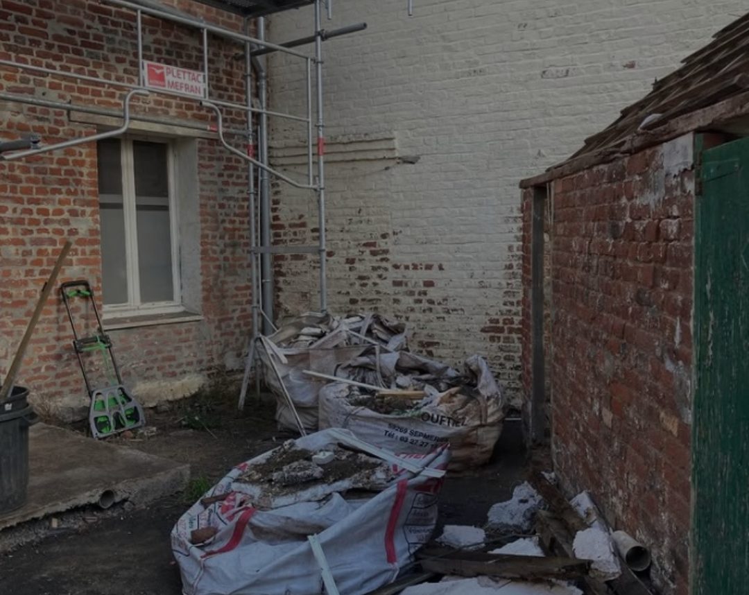 Cour encombrée de big-bags de gravats et de matériaux avant l'intervention